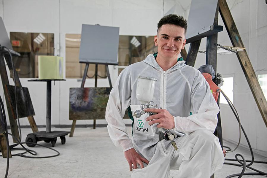 San Juan College student holding a paint sprayer in the auto body paint booth