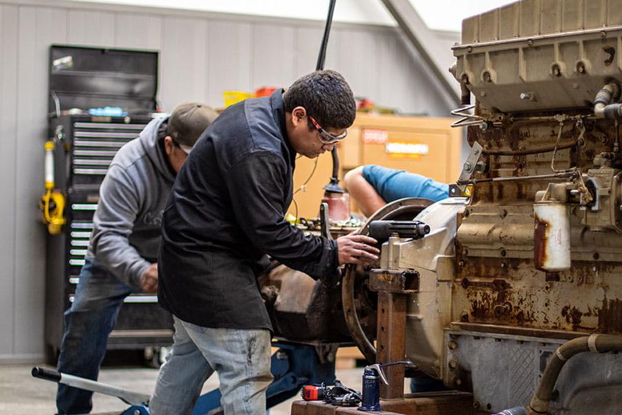 San Juan College students working on a large diesel engine